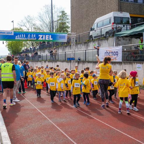 Gruppe von Kindern in gelben T-Shirts beim Ziel eines Laufwettbewerbs, umgeben von Zuschauern und Veranstaltern.