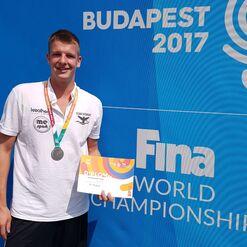 Junger Mann mit Medaille und Diplom für den vierten Platz vor der Hintergrundwand der FINA-Weltmeisterschaften 2017 in Budapest.