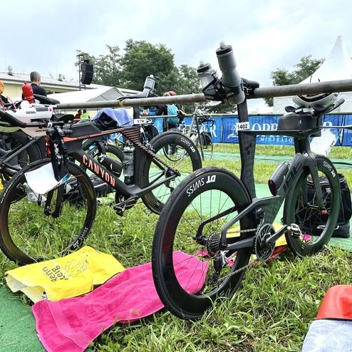 Zwei Sportfahrräder in einem Wettkampfbereich, neben Handtüchern auf grünem Teppichboden.