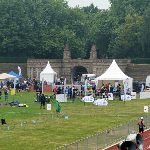 Sportliche Veranstaltung mit Zuschauern, Zelten und einer historischen Fassade im Hintergrund auf einer grünen Wiese.