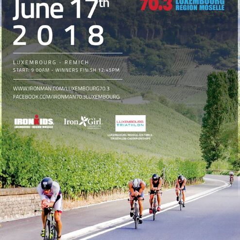 Teilnehmer beim Ironman 70.3 auf einer Straße in Luxemburg, umgeben von Weinbergen, mit einem klaren blauen Himmel.