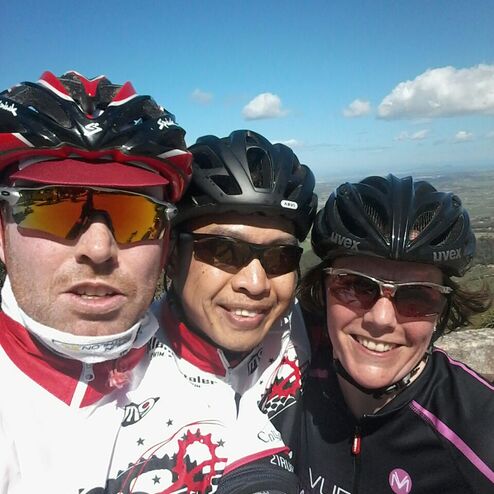 Drei Radfahrer machen ein Selfie vor einem klaren, blauen Himmel mit einigen Wolken im Hintergrund.