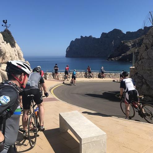 Radfahrer auf einer Uferstraße mit Blick auf das blaue Meer und bergige Küste an einem sonnigen Tag.