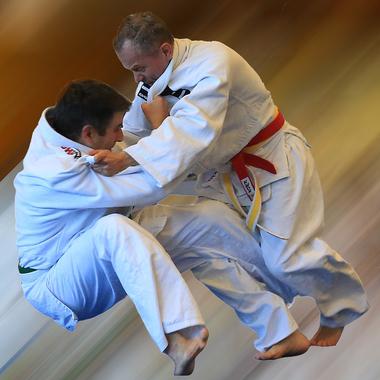 Zwei Judokas in weißen Gi kämpfen im Wettkampf, während einer den anderen mit einer Technik anhebt.