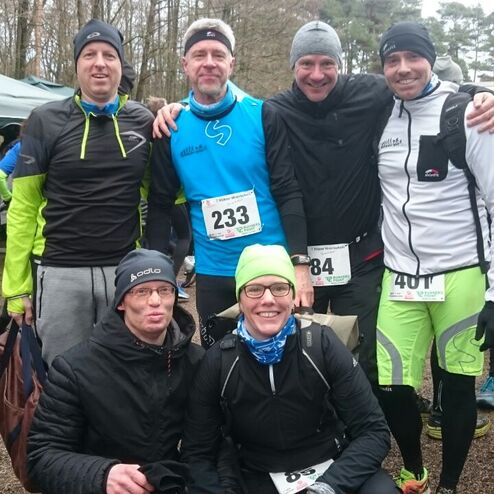 Sechs Teilnehmer eines Laufwettbewerbs posieren nach dem Rennen in sportlicher Kleidung auf einem Veranstaltungsgelände.