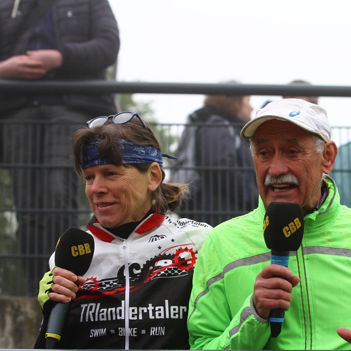 Zwei Personen sprechen in Mikrofone, eine trägt ein Innovatives Sportoutfit, die andere ein grünes Outfit und eine Mütze.