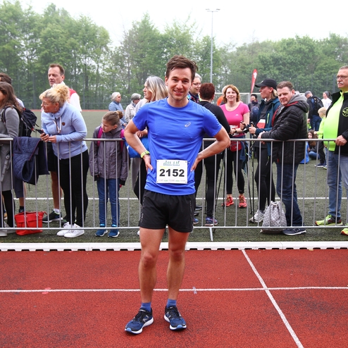 Läufer in blauer Sportbekleidung mit Startnummer 2152 steht auf der Laufbahn, umgeben von Zuschauern am Wettkampfort.