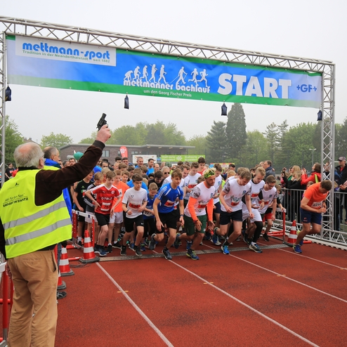 Startsignal für einen Laufwettbewerb: Läufer sprinten bei nebligem Wetter über eine rote Laufbahn.