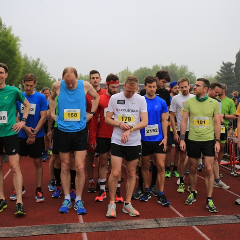 Gruppe von Läufern in Sportbekleidung auf einer Laufstrecke, bereit zum Start eines Wettkampfs.