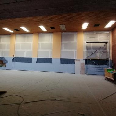 Blick in einen Renovierungsraum mit unvollendeten Wänden, Gerüst und abgedecktem Boden.