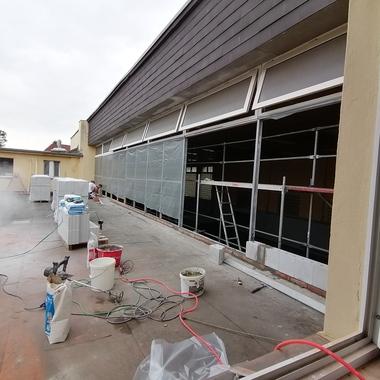 Bauarbeiter schneidet Baustellenmaterial auf einer Terrasse, umgeben von Werkzeugen und Materialien für die Renovierung.