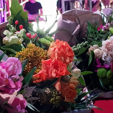 Bunte Blumensträuße mit verschiedenen Blüten und grünem Laub, teilweise in Geschenkpapiere eingewickelt.
