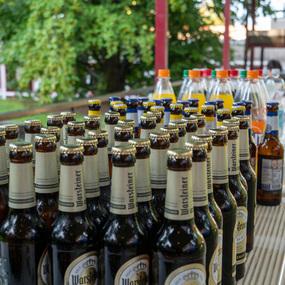 Tisch mit mehreren Warsteiner-Bierflaschen und verschiedenen Erfrischungsgetränken im Freien.