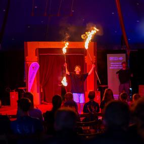 Junger Künstler führt im Zelt eine Feuershow mit Fackeln vor aufmerksamen Zuschauern durch.