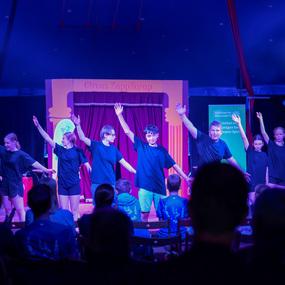 Eine Gruppe von jungen Darstellern in schwarzen T-Shirts führt eine Show im Zelt des Zirkus ZappZarap auf.