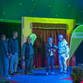 Vier Personen stehen auf einer Bühne im Zelt des Circus ZappZarap, während einer von ihnen ein Mikrofon hält.