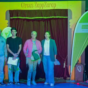Vier Personen stehen vor einem roten Vorhang mit der Aufschrift "Circus ZappZarap" und halten kleine Taschen in den H&auml;nden.