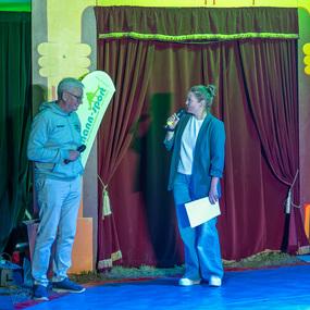 Zwei Personen stehen auf einer Zirkusb&uuml;hne, eine spricht ins Mikrofon, im Hintergrund das Zirkusschild "Circus ZappZarap".