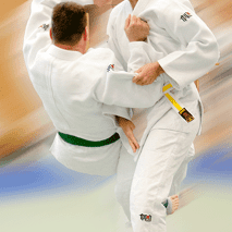 Zwei Judo-Kämpfer in weißen Judogis zeigen einen geworfenen Kampfgriff auf einer Judomatte.