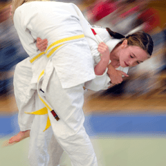 Zwei Judoka in weißen Anzügen führen einen Wurf im Training auf einer Tatami aus.