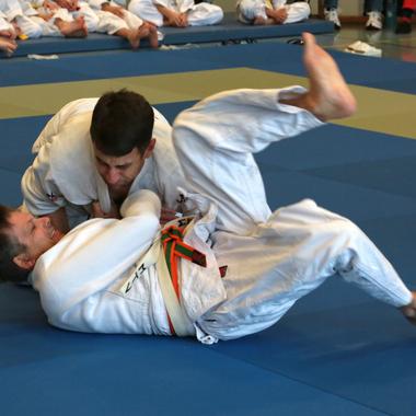 Zwei Judoka k&auml;mpfen auf einer blauen Matte, einer versucht, seinen Gegner in eine Position zu bringen.