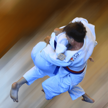 Zwei Judokas in Wettkampf: Einer führt einen Wurf aus, während der andere in der Luft schwebt.