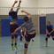 Zwei Volleyballspieler springen zum Blocken, während weitere Spieler auf dem Spielfeld in Aktion sind.