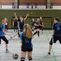 Volleyballspiel in einer Halle mit mehreren Spielern in uniformierten Trikots, ein Ball fliegt zwischen ihnen.