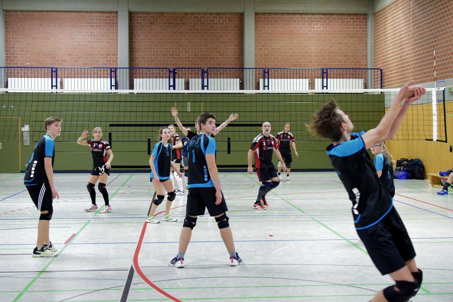 Jugendliche Volleyballspieler in Aktion, Ballwechsel während eines Spiels in einer Sporthalle.