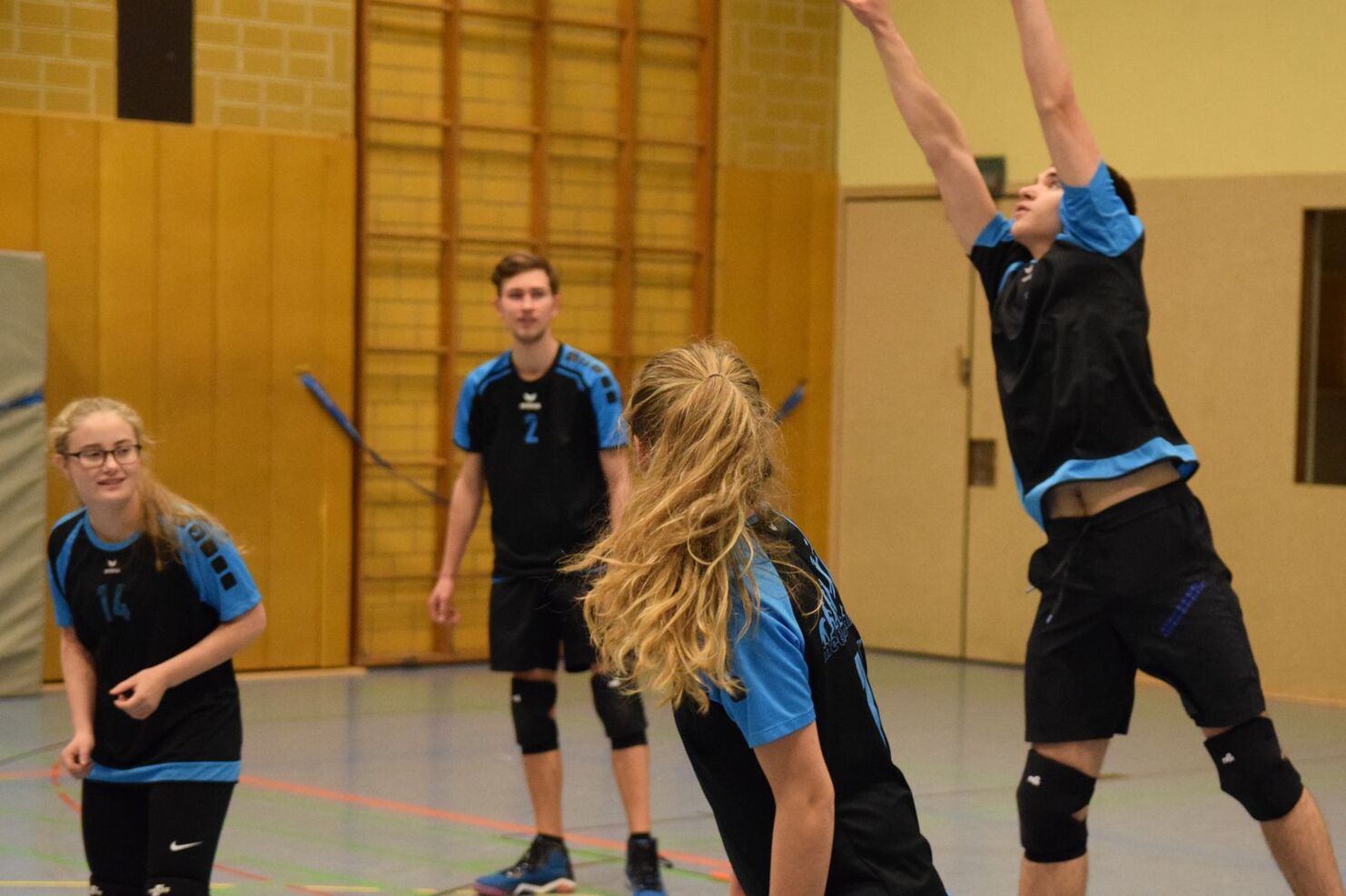 Viertelkreis einer Volleyballspielszene mit vier Spielern in Training, ein Spieler springt zum Angriffsschlag.