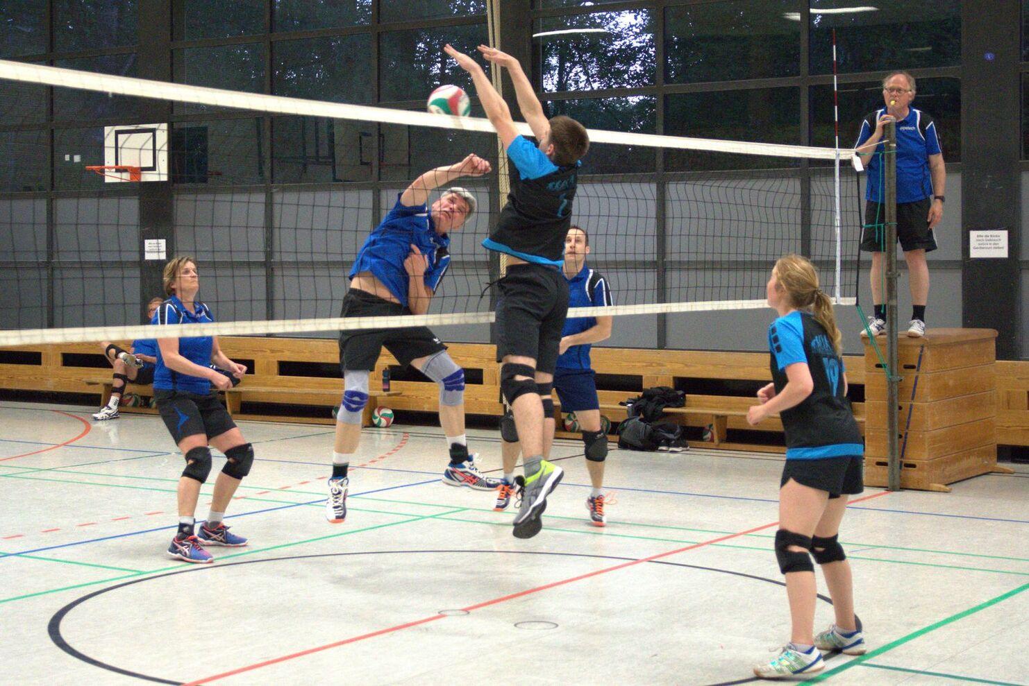 Spielszene im Volleyball mit mehreren Spielern in Bewegung, während ein Ball über das Netz gespielt wird.