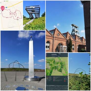 Silberner Obelisk vor blauer Himmel, im Hintergrund ein Hochofen und eine panoramische Landschaftskarte.