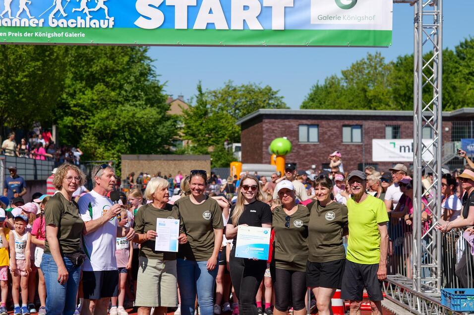Foto von der Bürgermeisterin und Helfern unter dem Starterbogen des Bachlaufs.