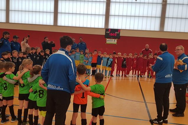 Gruppenszene mit Kindern in Fußballtrikots, die sich vor einem Trainer für ein Spiel versammeln.