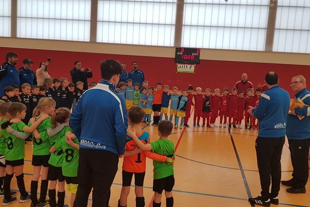 Gruppenszene mit Kindern in Fu&szlig;balltrikots, die sich vor einem Trainer f&uuml;r ein Spiel versammeln.