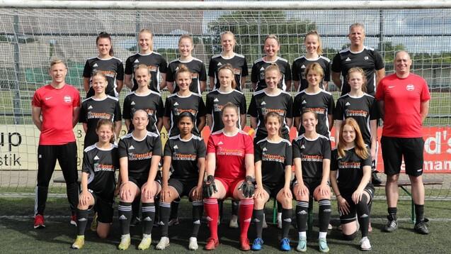 Mannschaftsbild einer Fußballmannschaft mit Trainer, alle in einheitlichen Trikots vor einem Fußballtor.