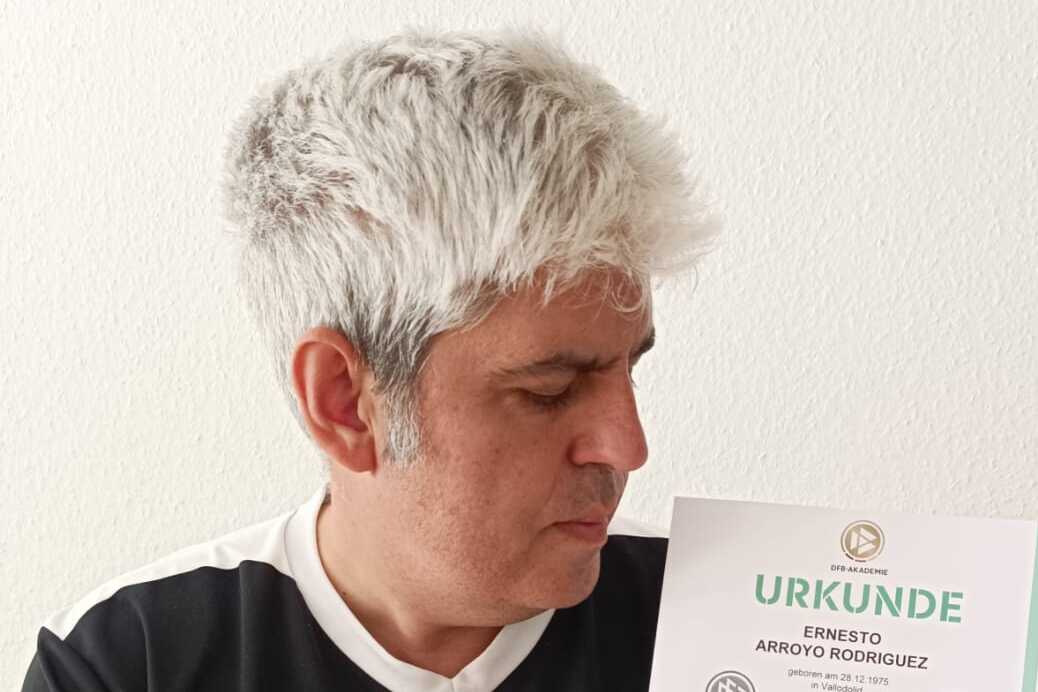 Mann mit grauen Haaren hält eine Trainer-C-Urkunde des Deutschen Fußball-Bundes in der Hand.