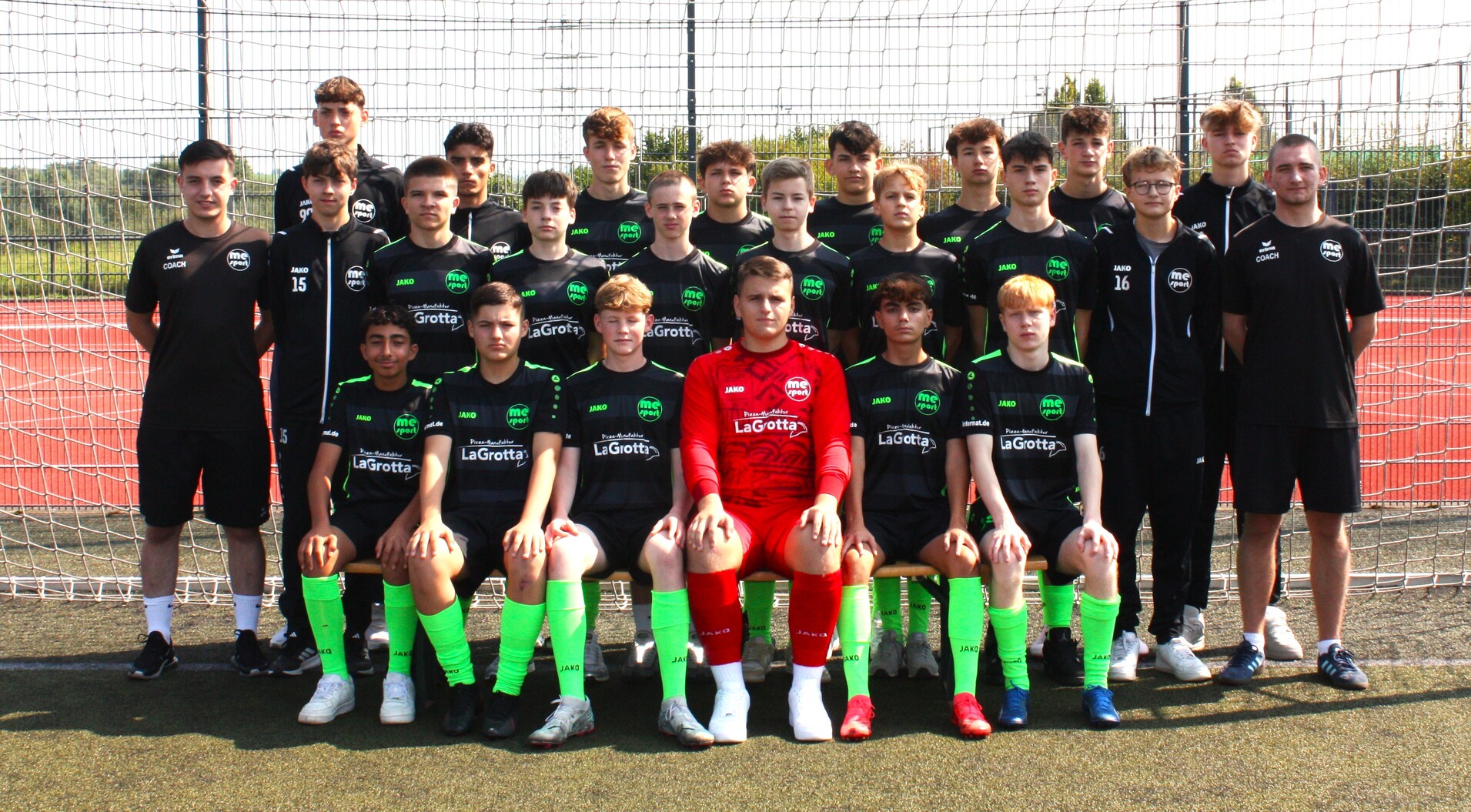 Gruppenfoto einer Fußballmannschaft mit Spielern in schwarzen und grünen Trikots, sowie einem Torwart in rotem Outfit.