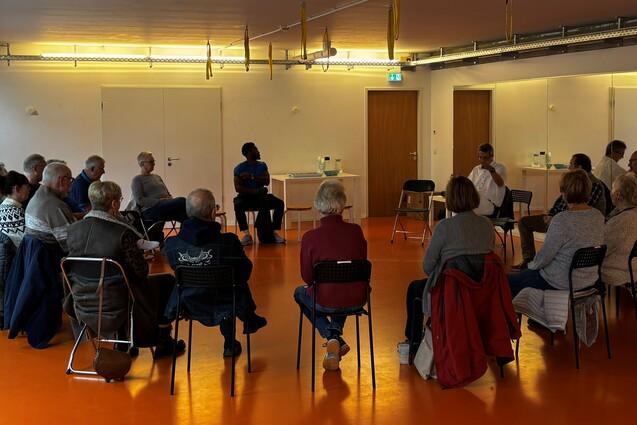 Menschen folgen sitzend im Kreis den Worten von Hr. Kober