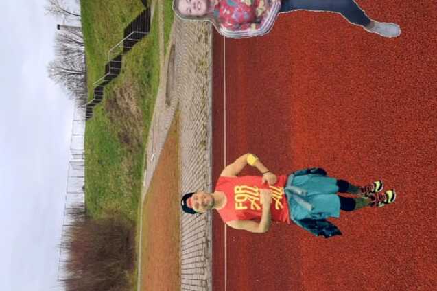 Drei Personen tanzen im Freien auf einem roten Sportplatz, mit einer Zumba-Beschriftung über ihnen.