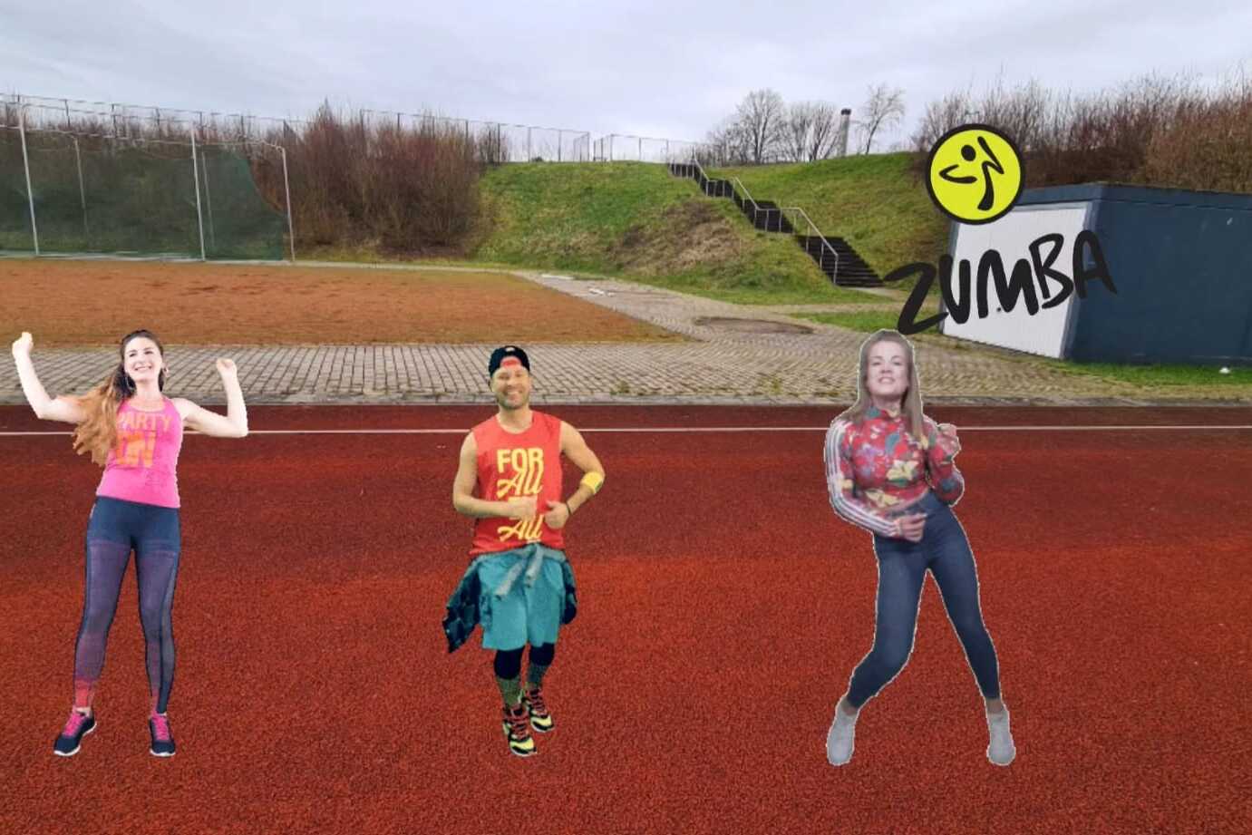 Drei Personen tanzen im Freien auf einem roten Sportplatz, mit einer Zumba-Beschriftung &uuml;ber ihnen.