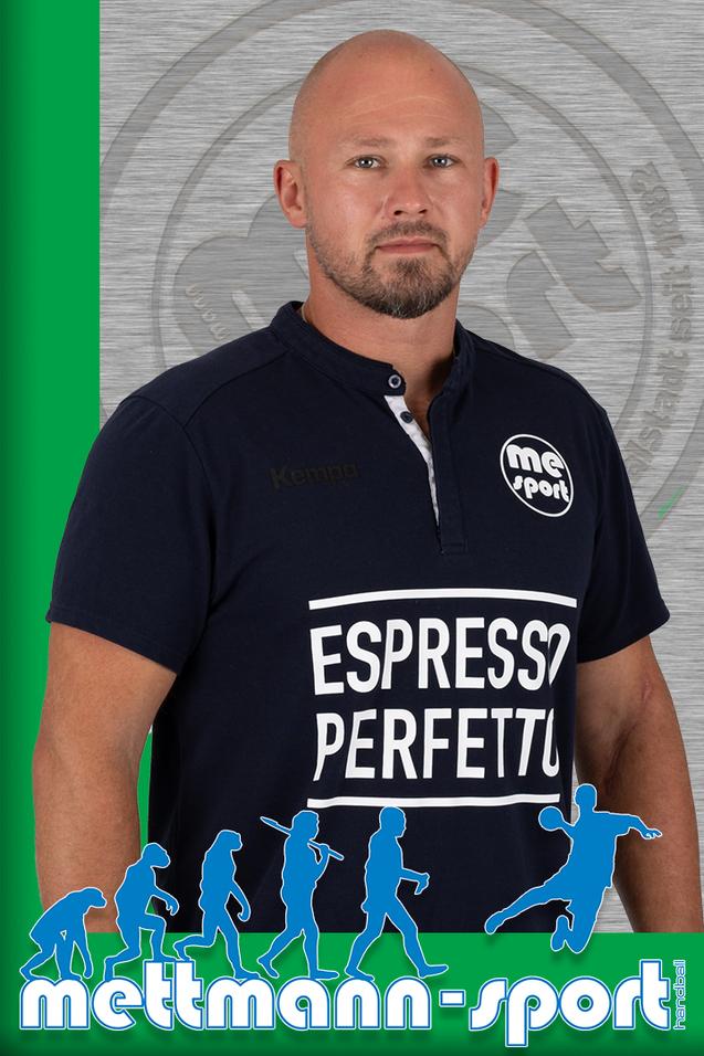 Mann mit Glatze und Bart trägt ein Polohemd mit dem Aufdruck „Espresso Perfetto“ vor einem grauen Hintergrund.