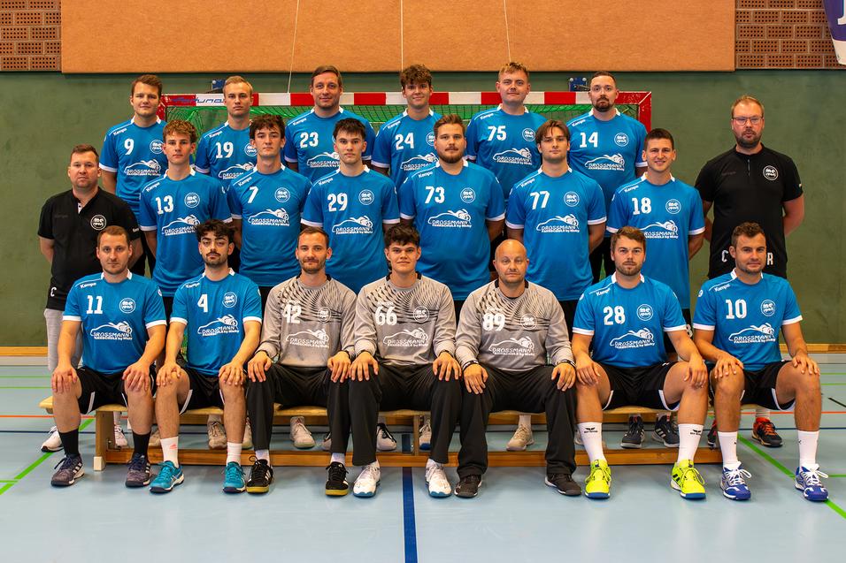 Mannschaftsfoto einer Handballmannschaft in blauen Trikots, Gruppenaufstellung in einer Sporthalle.