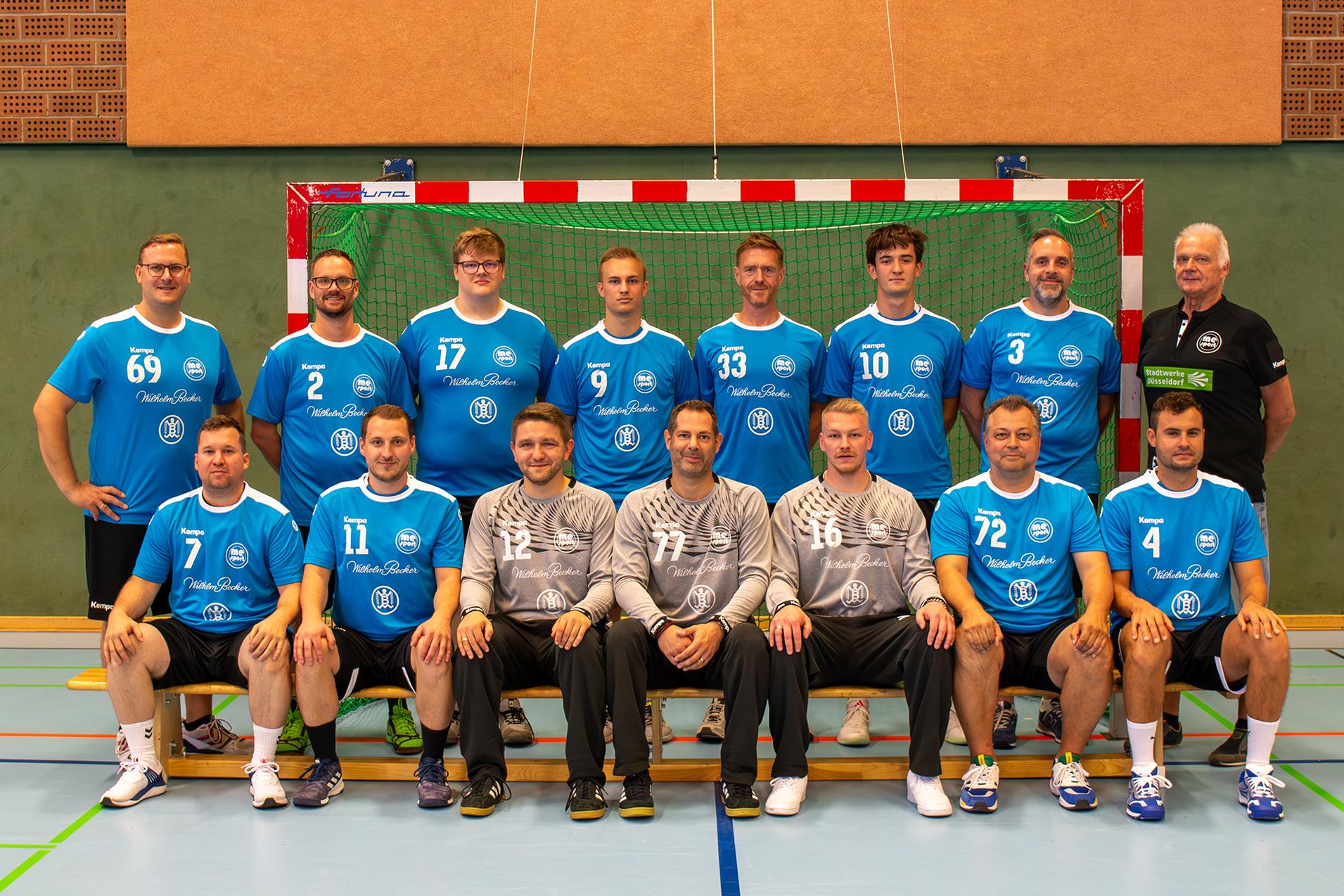 Mannschaftsfoto einer Handballmannschaft in blauen Trikots vor einem Tor in der Sporthalle.