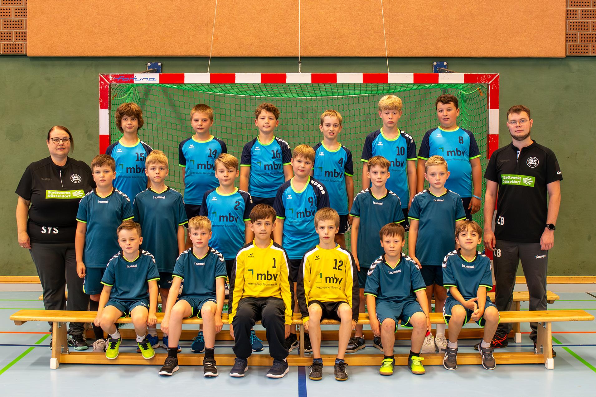 Mannschaftsfoto einer Handball-Jugend, bestehend aus 15 Jungen und 2 Betreuern vor einem Handballtor in einer Sporthalle.