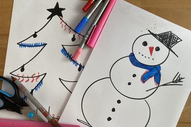 Zwei gemalte Bilder: ein Weihnachtsbaum und ein Schneemann, umgeben von Schere und bunten Markern auf einem Tisch.