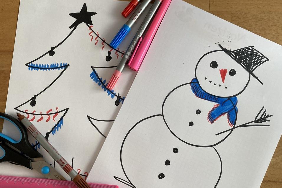 Zwei gemalte Bilder: ein Weihnachtsbaum und ein Schneemann, umgeben von Schere und bunten Markern auf einem Tisch.