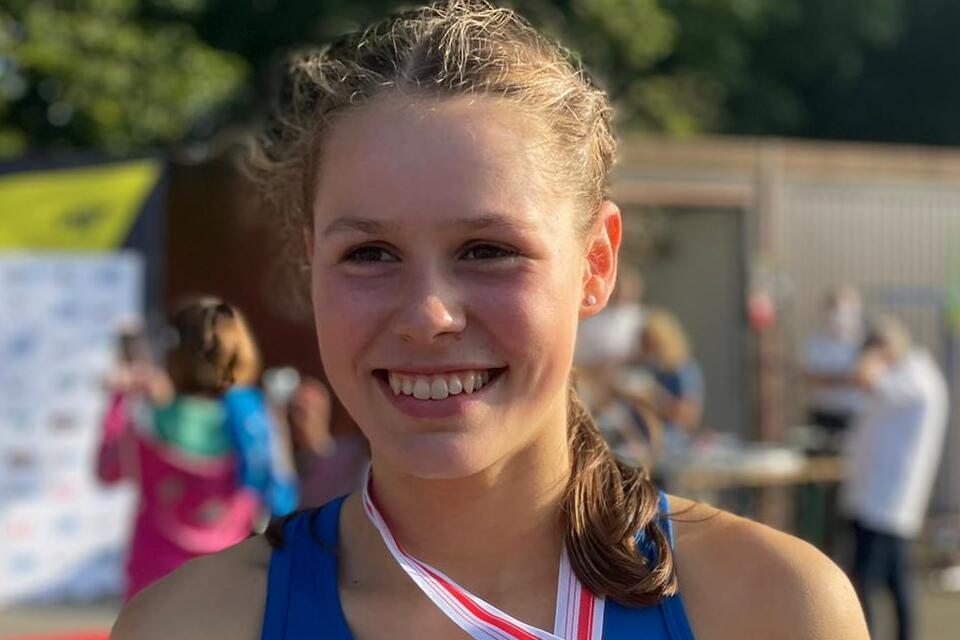 Läuferin hält Urkunde und Medaille nach dem Sieg über 3000 m bei den Deutschen Meisterschaften U16 in der Jugend W15.