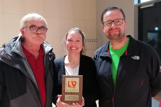 Drei Personen stehen lächelnd zusammen und halten eine Auszeichnung mit dem Logo „LV Nordrhein“.