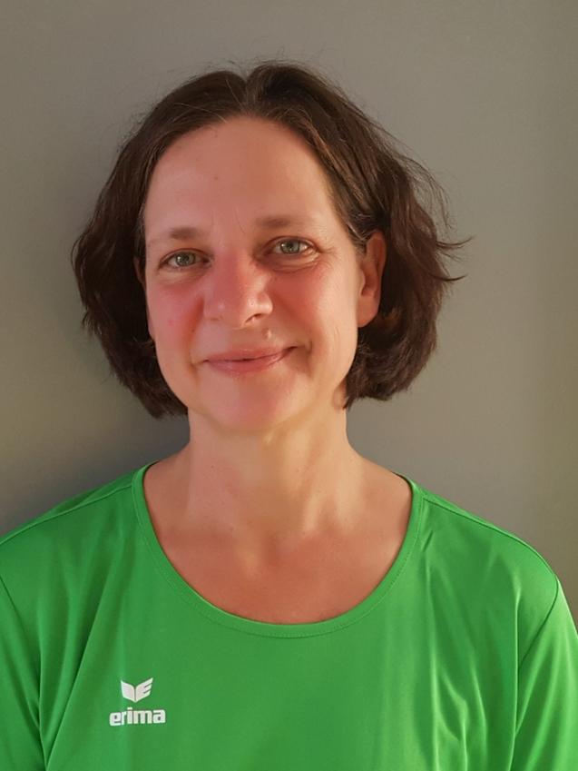 Frau mit schulterlangen Haaren in einem grünen Sportshirt vor grauem Hintergrund, lächelt freundlich in die Kamera.